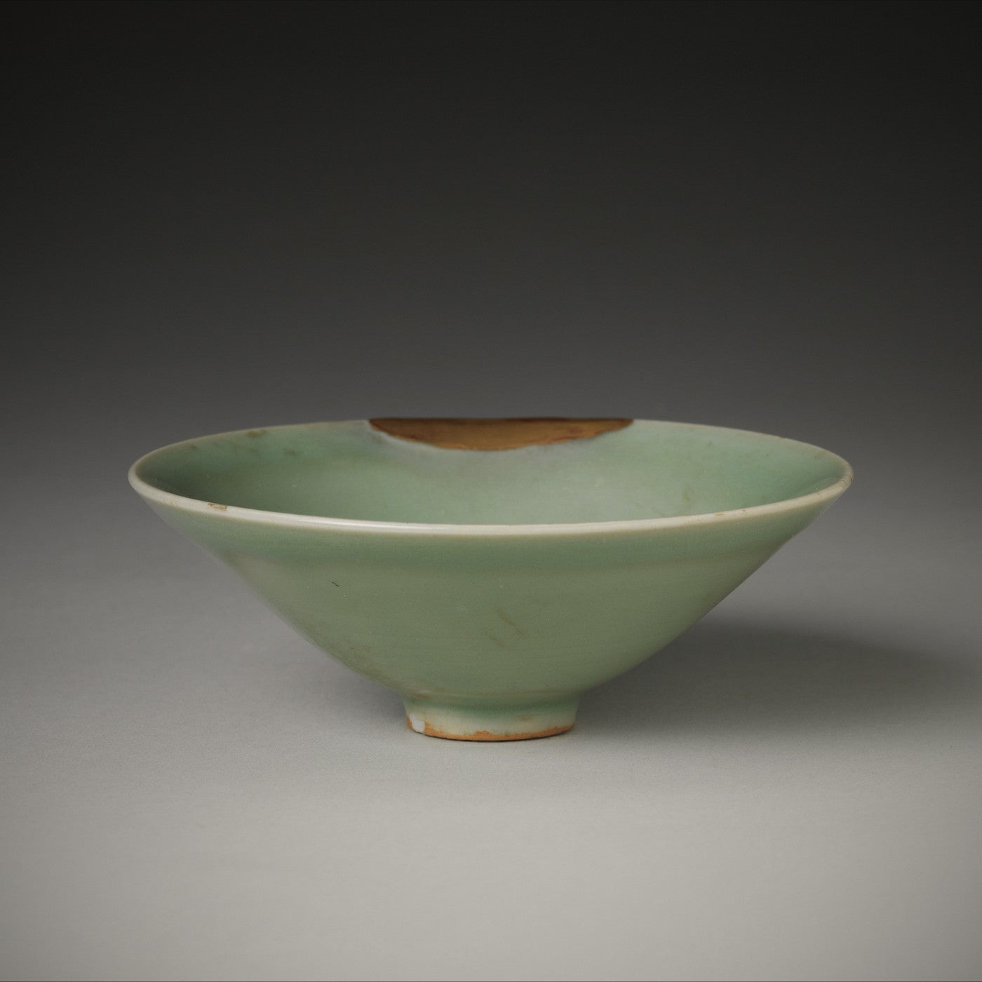 A celadon bowl with a gilt rim